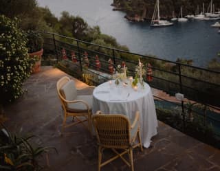 On the sub-lit terrace, a dining table with candles waits for special guests, as bay views start to melt in the evening light.