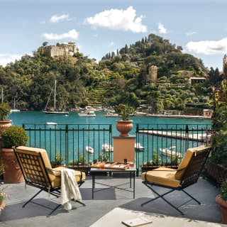 Hotel suite terrace with a breakfast table and chairs, overlooking Portofino Bay