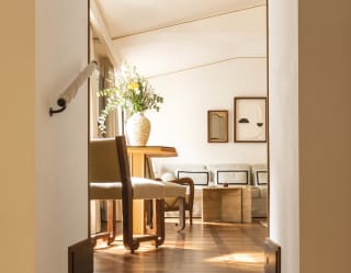 Off white walls and mid-century cream furnishings with accents of black are paired with golden woods for a timeless quality
