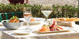 Table set on the piazzetta with two seafood dishes, someone walks by in the distance
