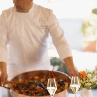 A couple holds hands as the chef serves a dish tableside