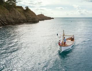Traditional Italian gozzo boat sailing in to a bay near Portofino