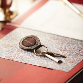 Close-up of a key with a tartan and leather fob on a paisley-patterned card