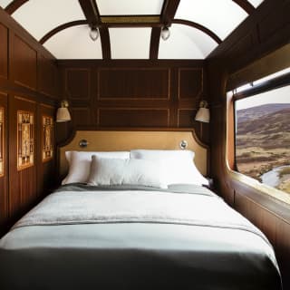 Looking into the Grand Suite bedroom where a bed sits between marquetry wall panels and a window on to the Scottish Highlands.