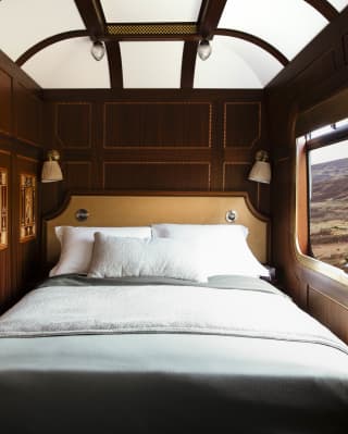 Looking into the Grand Suite bedroom where a bed sits between marquetry wall panels and a window on to the Scottish Highlands.