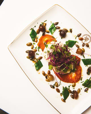 Birds-eye-view of a mozzarella salad surrounded by capers and snap peas