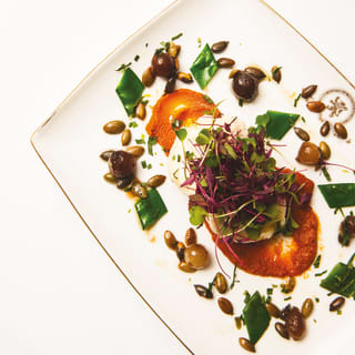 Birds-eye-view of a mozzarella salad surrounded by capers and snap peas