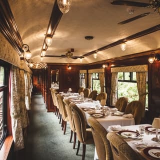 Tables-for-four lining a wood-panelled dining car with elegant window drapes