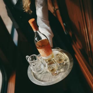 Close-up of a tray carrying a bottle of Glenmorangie single malt whisky with two whisky glasses and a jug of water.