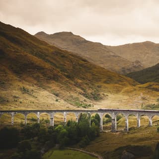 In a valley scene of plunging hillsides, the Royal Scotsman looks miniature as it crosses the span of the Glenfinnan Viaduct.