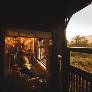 View from an open-air observation deck through a glass window of a train lounge