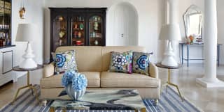 White columns support the ceiling of a lavish sitting room, with marble floor and display cabinet of colourful Sicilian ceramics