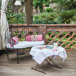 Ornate wrought-iron daybed with vibrant cushions, prepared for spa treatments