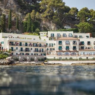 Grand hotel with clay tiled roof and cream coloured arches on the shoreline