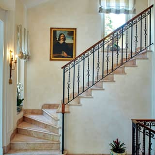 Renaissance portrait hanging beside clay tiled stairs with wrought-iron railings