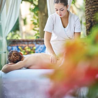 Spa therapist massaging a guest in an open air spa gazebo