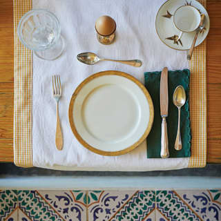 Birds-eye-view of a table setting with a gold-rimmed base plate and a boiled egg
