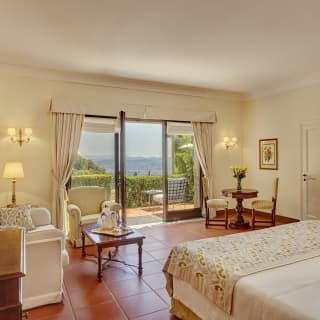 Glass doors open onto a private furnished balcony with views across the valley. A champagne ice bucket waits on a table