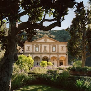 The Michelangelo-designed facade stands with palest pink walls amid a sea of green as lush hills climb up behind the gardens