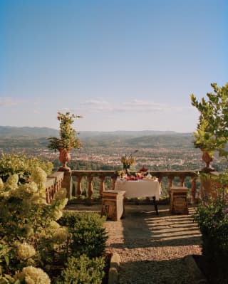 A lunch table on a rustic terrace overlooking Florence bakes in heat and romance, taken by Photographer François Halard.