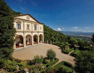 Classical exterior of a former Italian monastery with arched cloisters and a grand drive