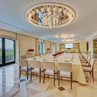 Large banquet table set for a meeting in a marble-tiled bright and airy room