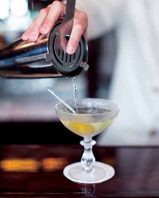 Close-up of a martini cocktail being poured from a shaker into a coupe glass