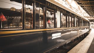 The windows and high gloss carriages extending down the platform reflects the station and its ironwork roofline