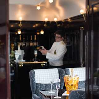 Champagne bottle in a Lalique glass cooler on a vintage train carriage table
